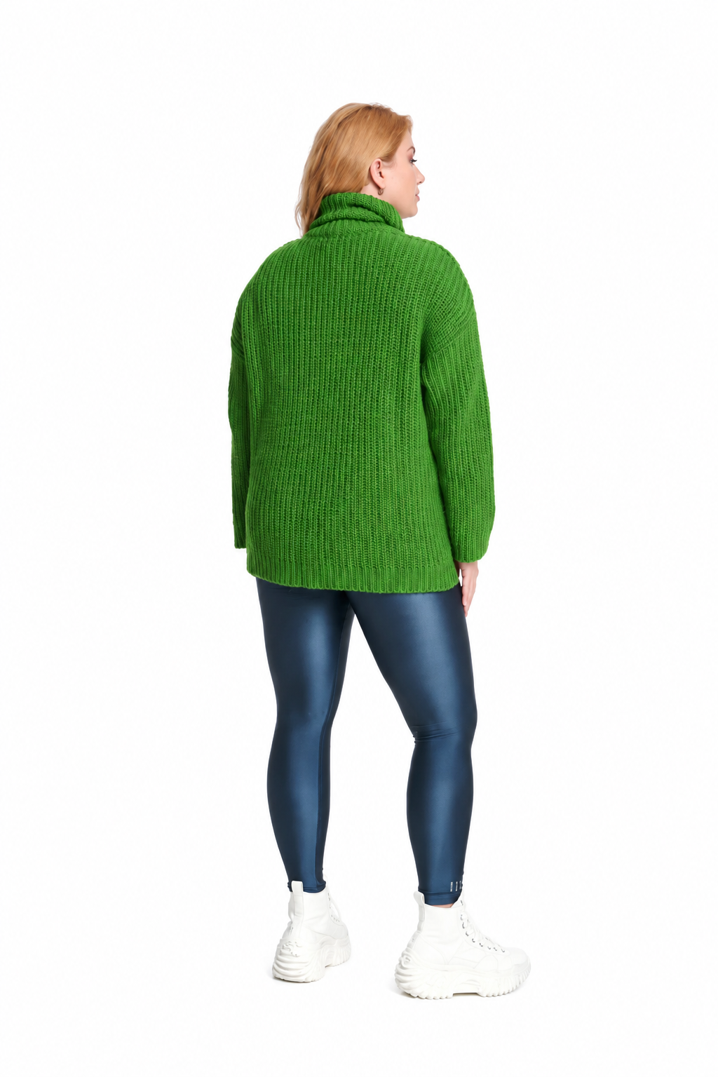 A woman is shown from the back wearing an oversized green ribbed knit turtleneck sweater, dark blue leggings, and white sneakers against a plain white background.