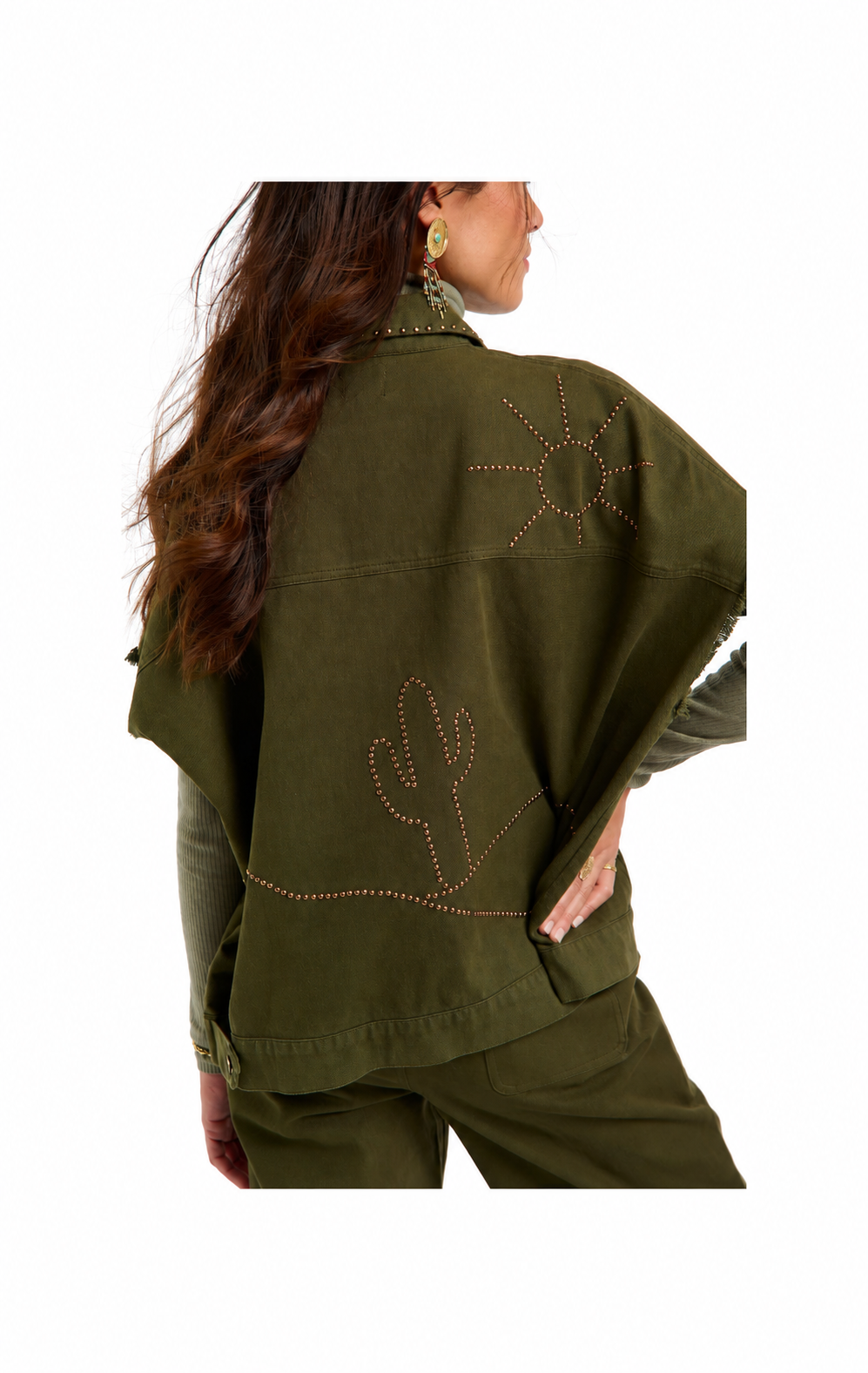 A woman shown from the back wearing an olive green poncho-style jacket with embroidered desert motifs, including a sun and cactus, on a plain white background.