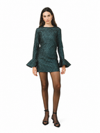 A model wearing a dark green sequined mini dress with long flared sleeves, paired with sheer black tights and black high-heeled sandals, set against a plain white background.