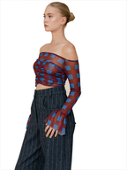A model wearing a sheer off-the-shoulder long-sleeve crop top with a red and blue checkered pattern, paired with dark pinstriped trousers, against a plain white background.