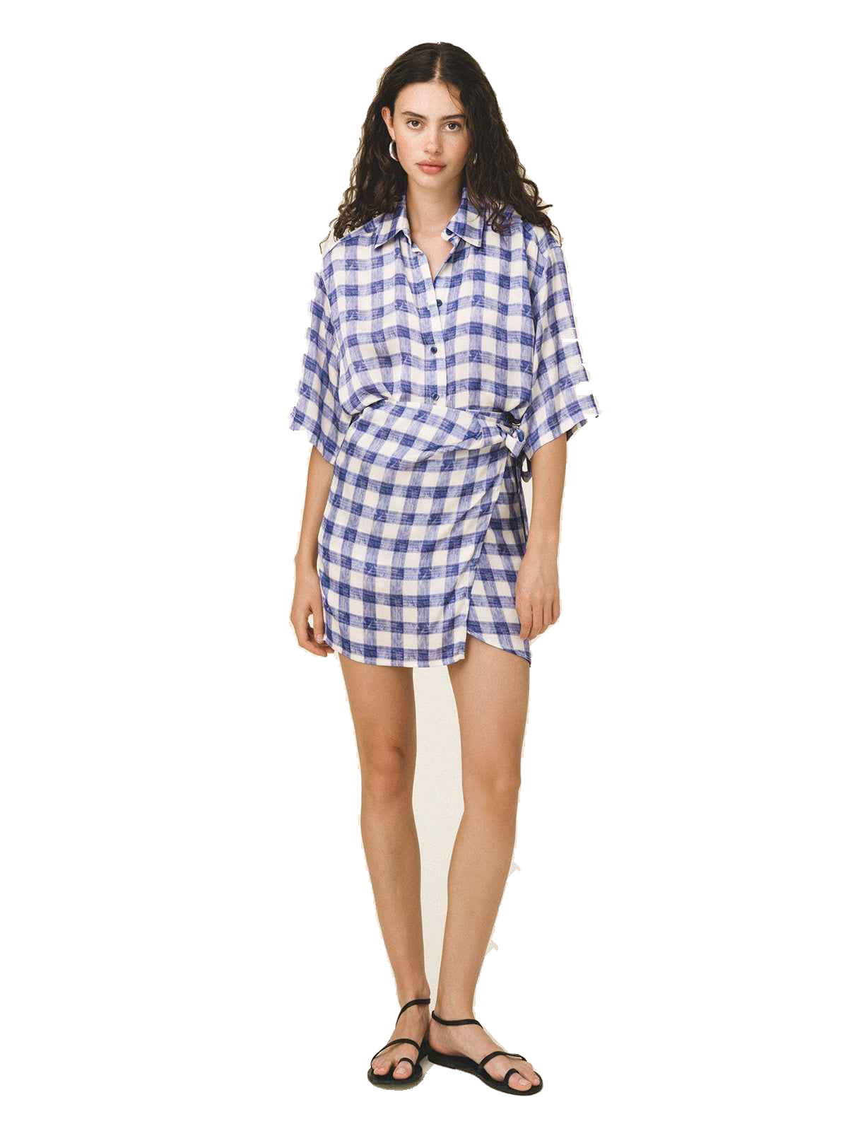 A woman modeling a blue and white gingham wrap shirt dress with short sleeves and a tie waist, paired with black flat sandals, against a plain white background.