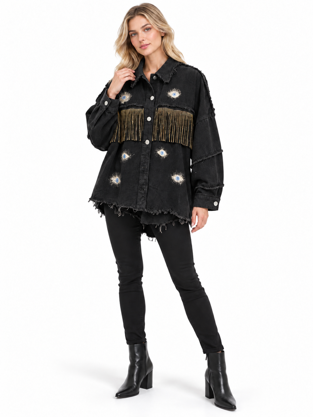A woman modeling a black distressed denim jacket with fringe and floral embroidery, paired with black skinny jeans and black ankle boots, on a white studio background.