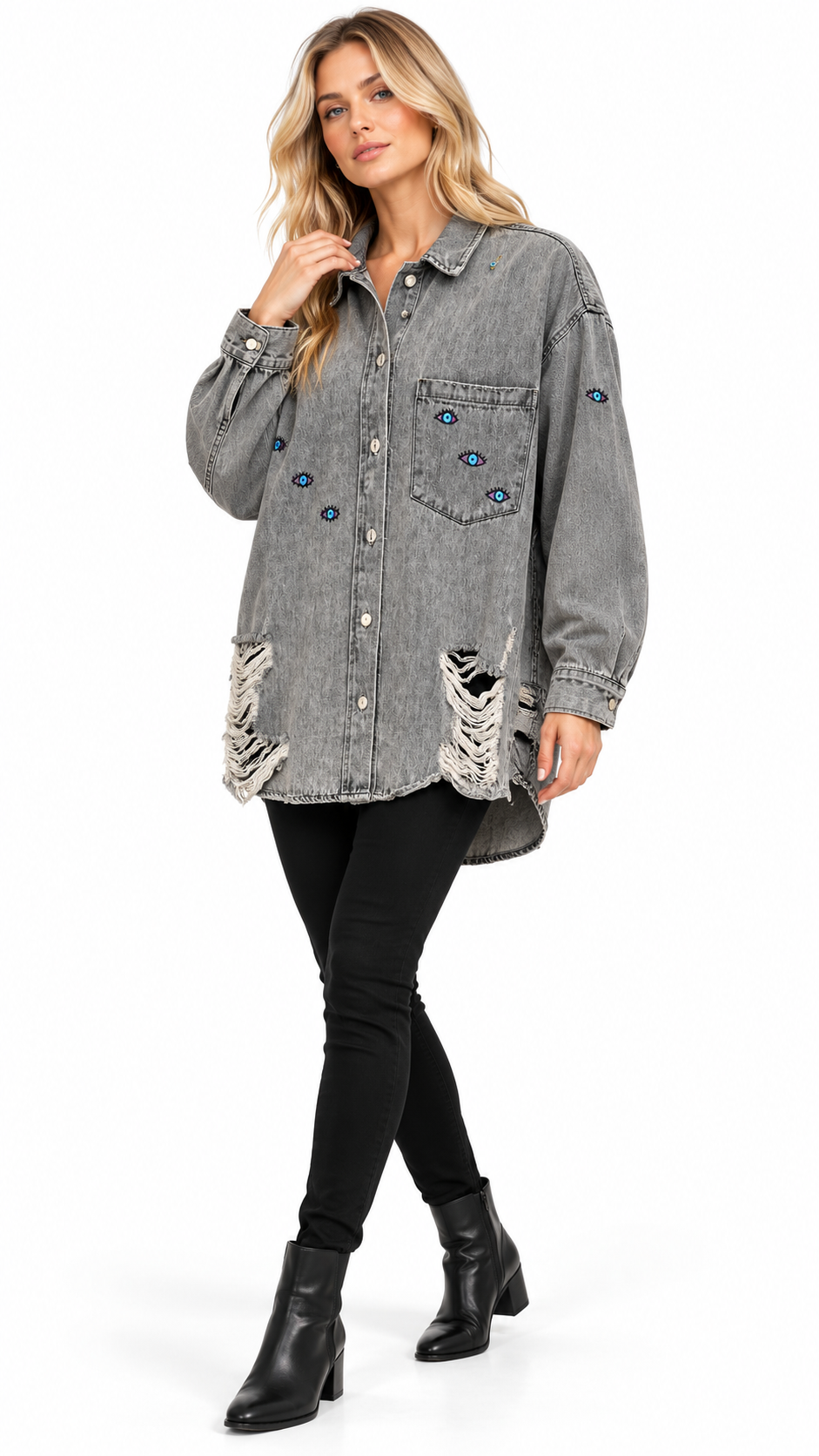 A woman models a washed gray denim shirt jacket with distressed details and blue rhinestone embellishments, paired with black pants and black ankle boots against a white studio background.