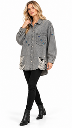 A woman models a washed gray denim shirt jacket with distressed details and blue rhinestone embellishments, paired with black pants and black ankle boots against a white studio background.