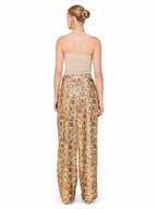 A woman shown from the back wearing a strapless beige bandeau top and high-waisted wide-leg trousers with a beige, brown, and gold snakeskin pattern, set against a plain white background.