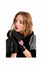 A model wearing a black knit glove with a heart-shaped embroidered patch featuring a red, white, and blue eye design, paired with a black and silver textured jacket against a plain white background.