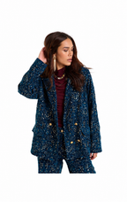 A woman modeling a dark blue sequined blazer and matching pants set with gold buttons, worn over a burgundy top, against a plain white background.