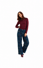 A woman modeling a dark blue patterned wide-leg trouser set with a burgundy long-sleeve top, standing against a solid white background.