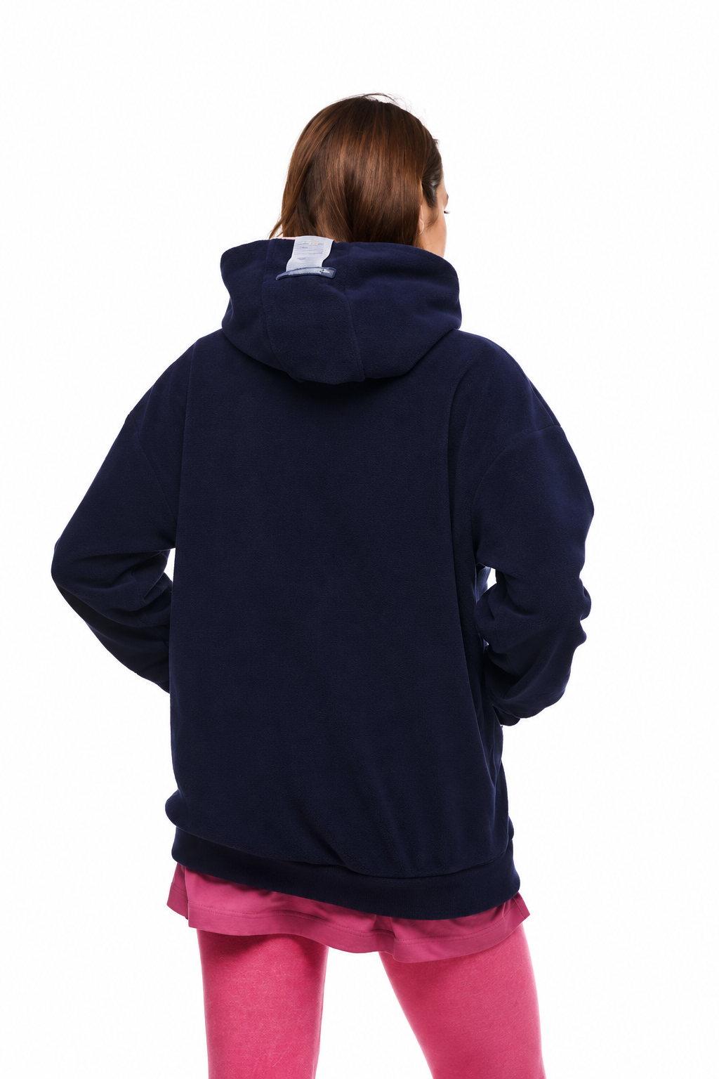 A person shown from the back wearing an oversized navy blue hoodie over a pink shirt and pink leggings, against a plain white background.