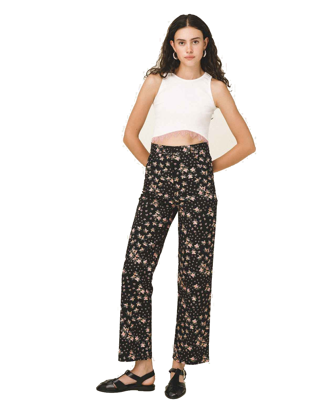 A model wearing black wide-leg trousers with a beige floral pattern, paired with a white sleeveless crop top and black Mary Jane shoes, set against a plain white background.