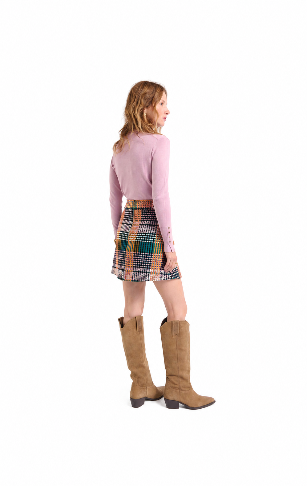 A woman shown from the back wearing a light pink long-sleeve top, a multicolor plaid mini skirt, and tan knee-high boots, photographed against a plain white background.