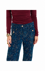 A person wearing dark teal blue pants with a gold speckled pattern and a maroon long-sleeve top, shown from the chest down against a plain white background.