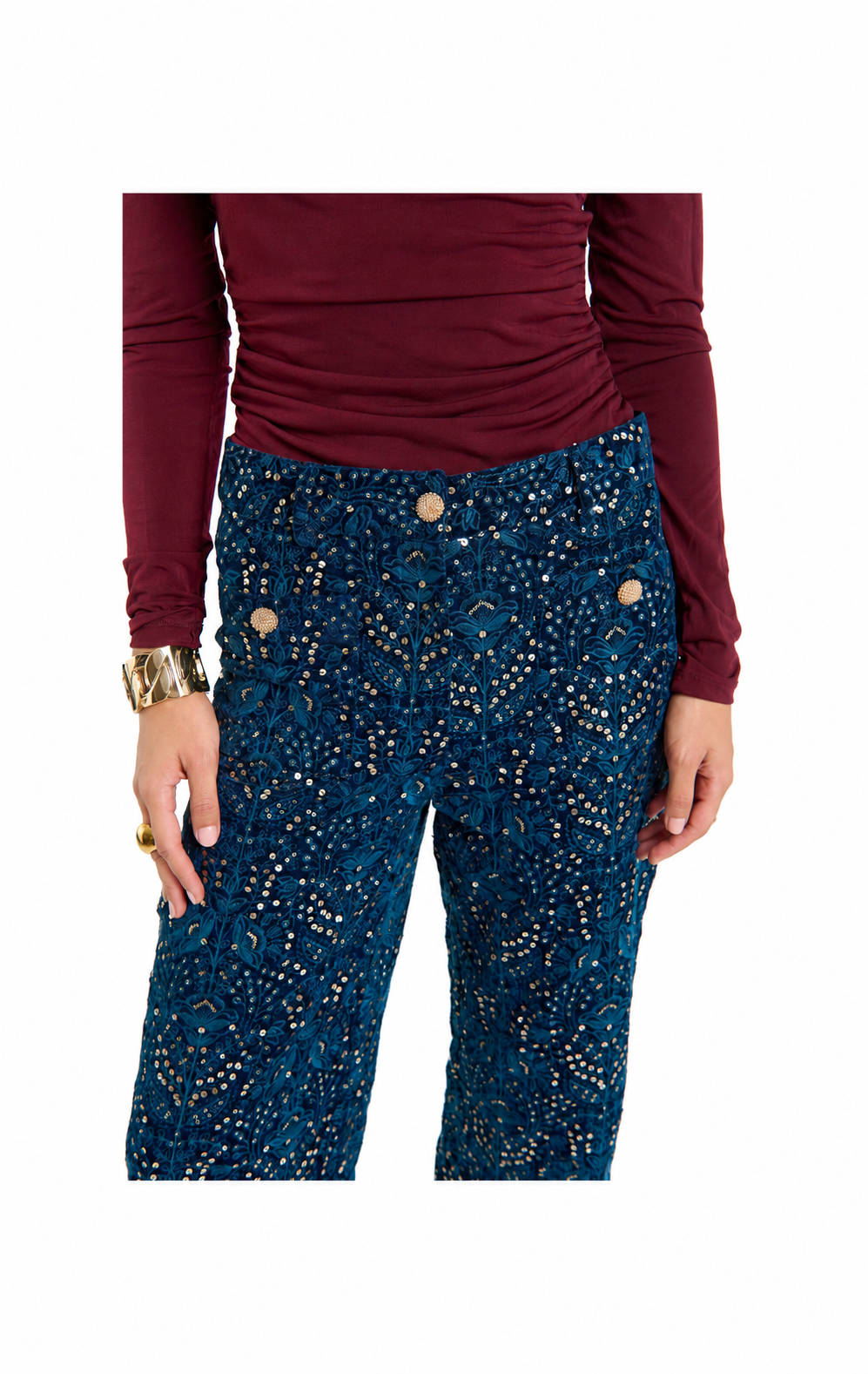 A person wearing dark teal blue pants with a gold speckled pattern and a maroon long-sleeve top, shown from the chest down against a plain white background.