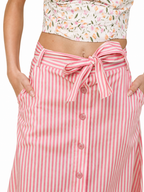 A close-up of a model wearing a pink and white vertically striped button-front skirt with a matching fabric tie belt at the waist. The model is also wearing a floral print crop top, shown from the waist down against a plain white background.