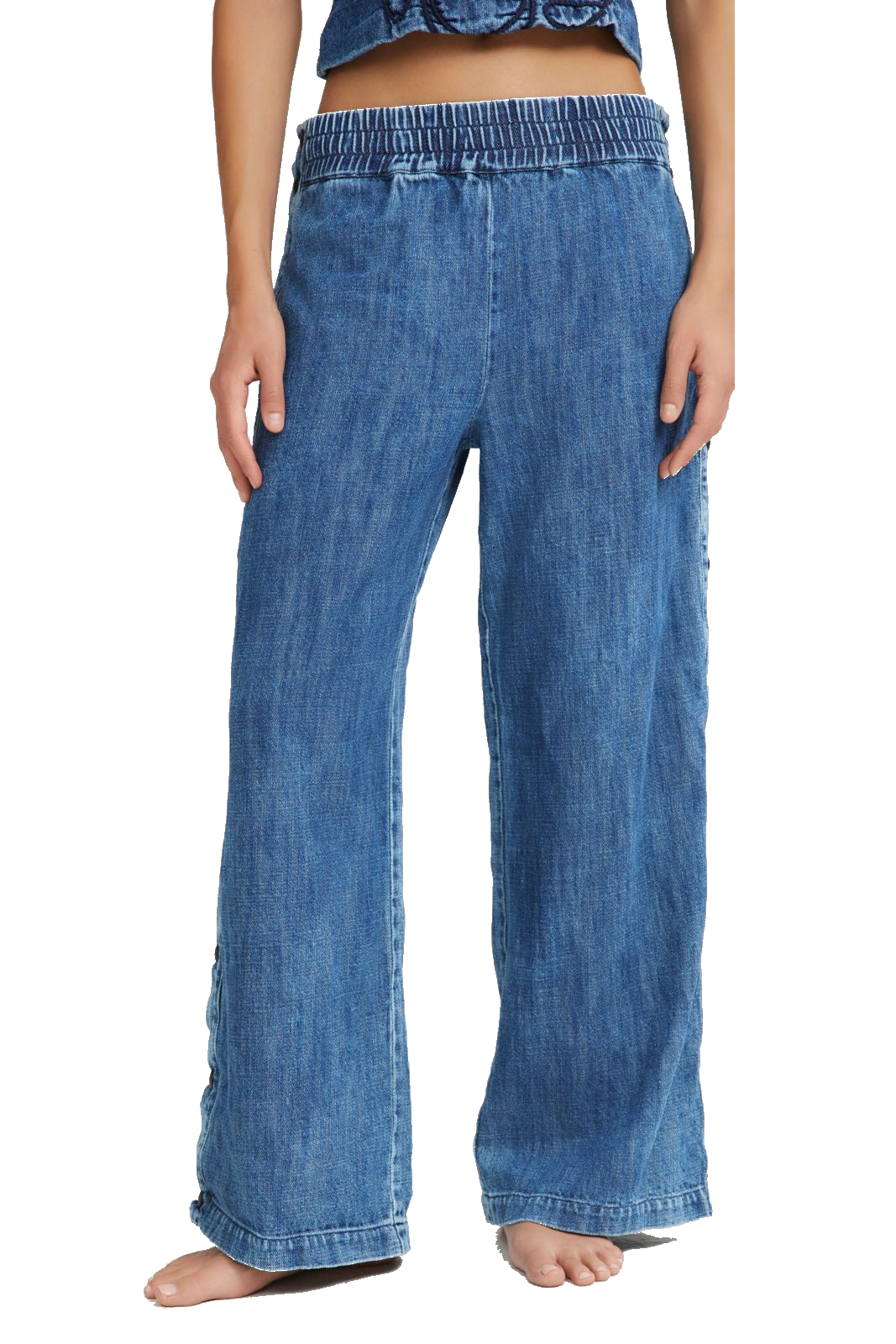 A person wearing wide-leg blue denim pants with an elastic waistband, shown from the waist down against a plain white background.