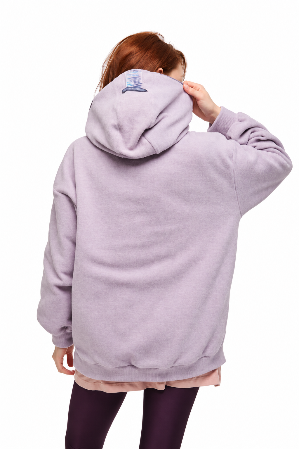 A person shown from the back wearing an oversized light lavender hoodie, with dark leggings and a light pink undershirt visible, against a plain white background.