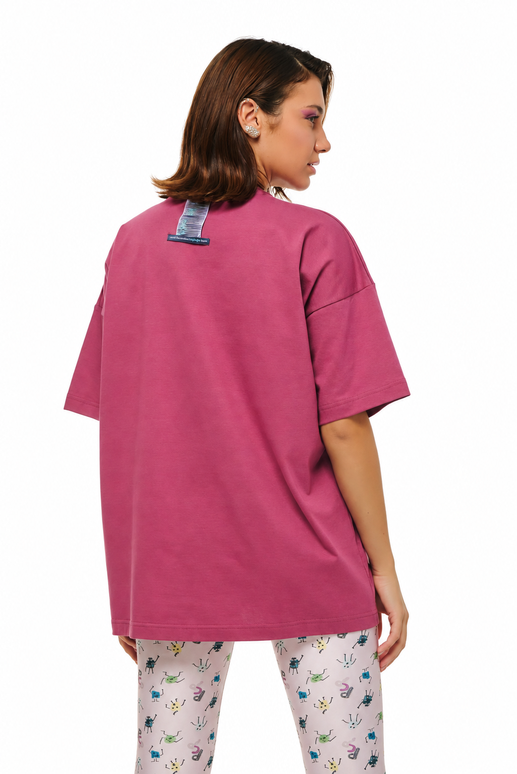 A woman shown from the back wearing an oversized magenta-pink t-shirt and white leggings with a colorful floral pattern, set against a plain white background.