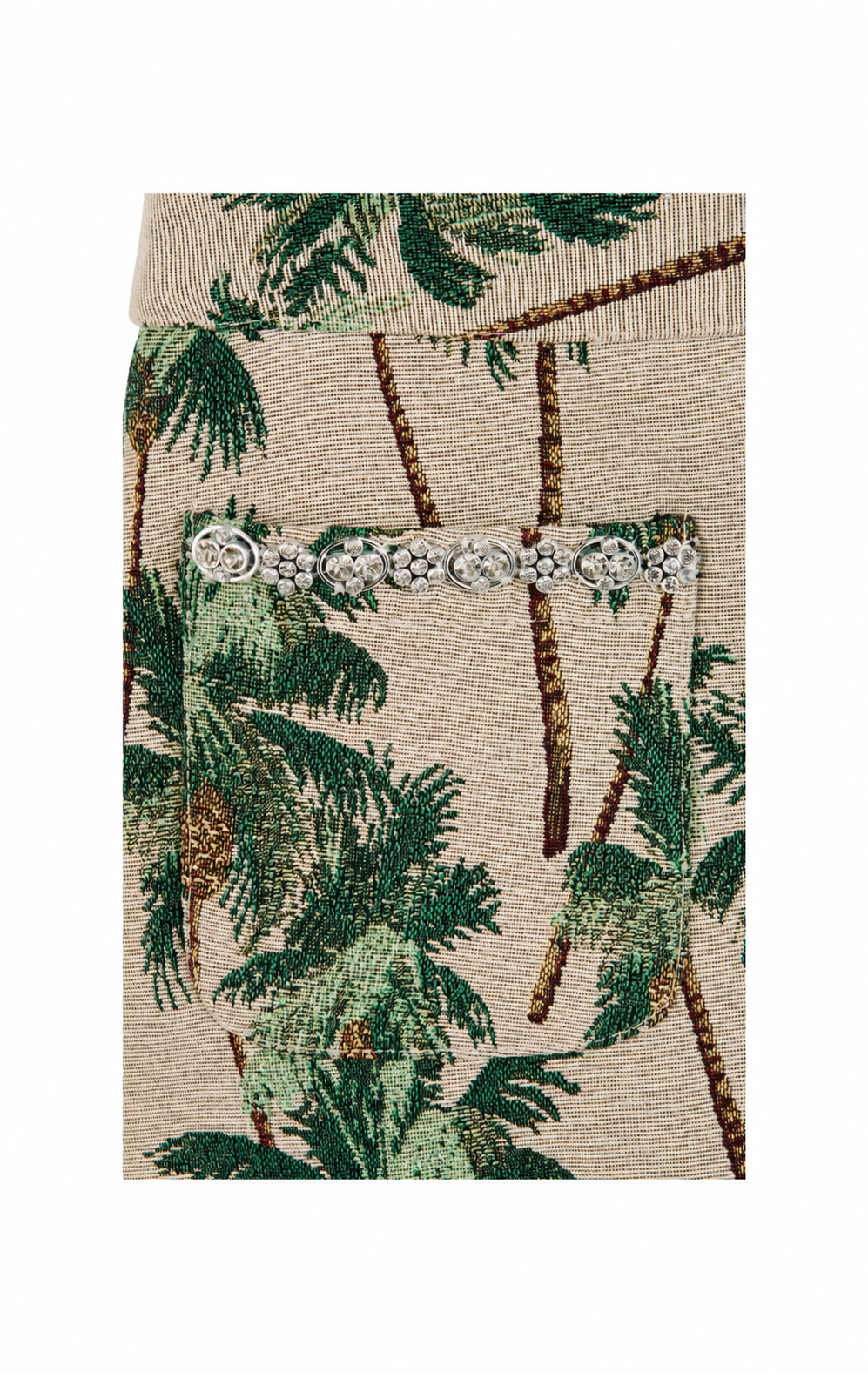 A close-up of a woven fabric featuring a green palm tree pattern on a beige background, with a horizontal row of silver rhinestone embellishments across the center.