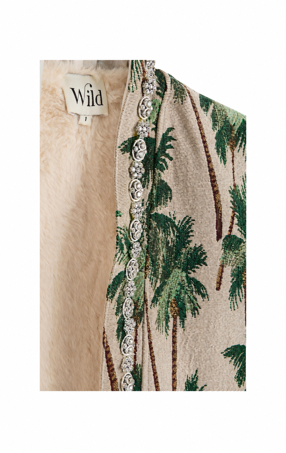 Close-up of a beige woven jacket or cardigan with a green palm tree pattern, a decorative silver-toned beaded trim, and a cream faux-fur lining. A brand label reading 'Wild' is visible.