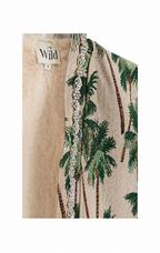Close-up of a beige woven jacket or cardigan with a green palm tree pattern, a decorative silver-toned beaded trim, and a cream faux-fur lining. A brand label reading 'Wild' is visible.