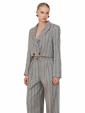 A model wearing a gray double-breasted pinstripe blazer and matching trousers, styled with a thin brown belt, against a plain white background.
