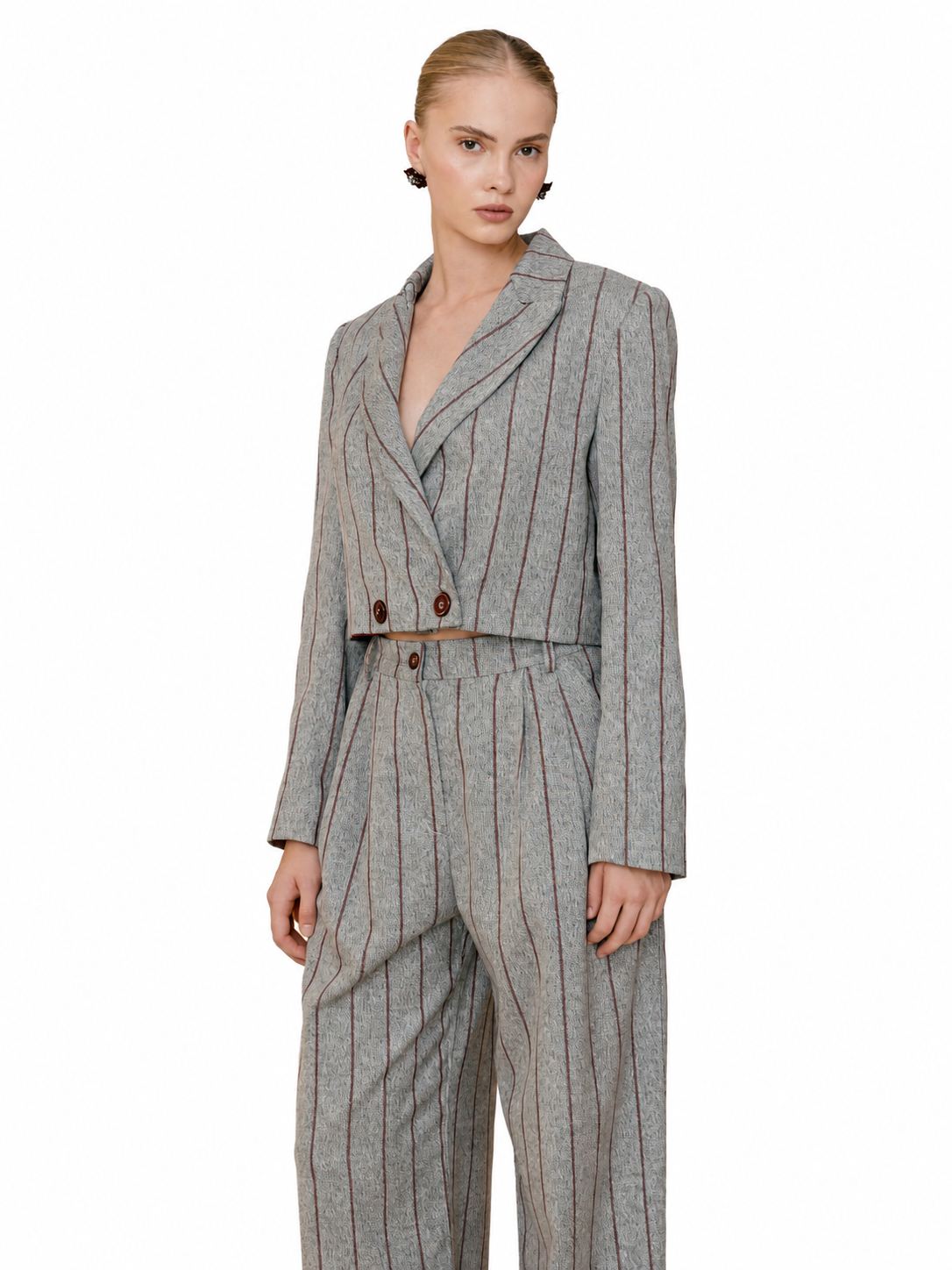 A model wearing a gray double-breasted pinstripe blazer and matching trousers, styled with a thin brown belt, against a plain white background.