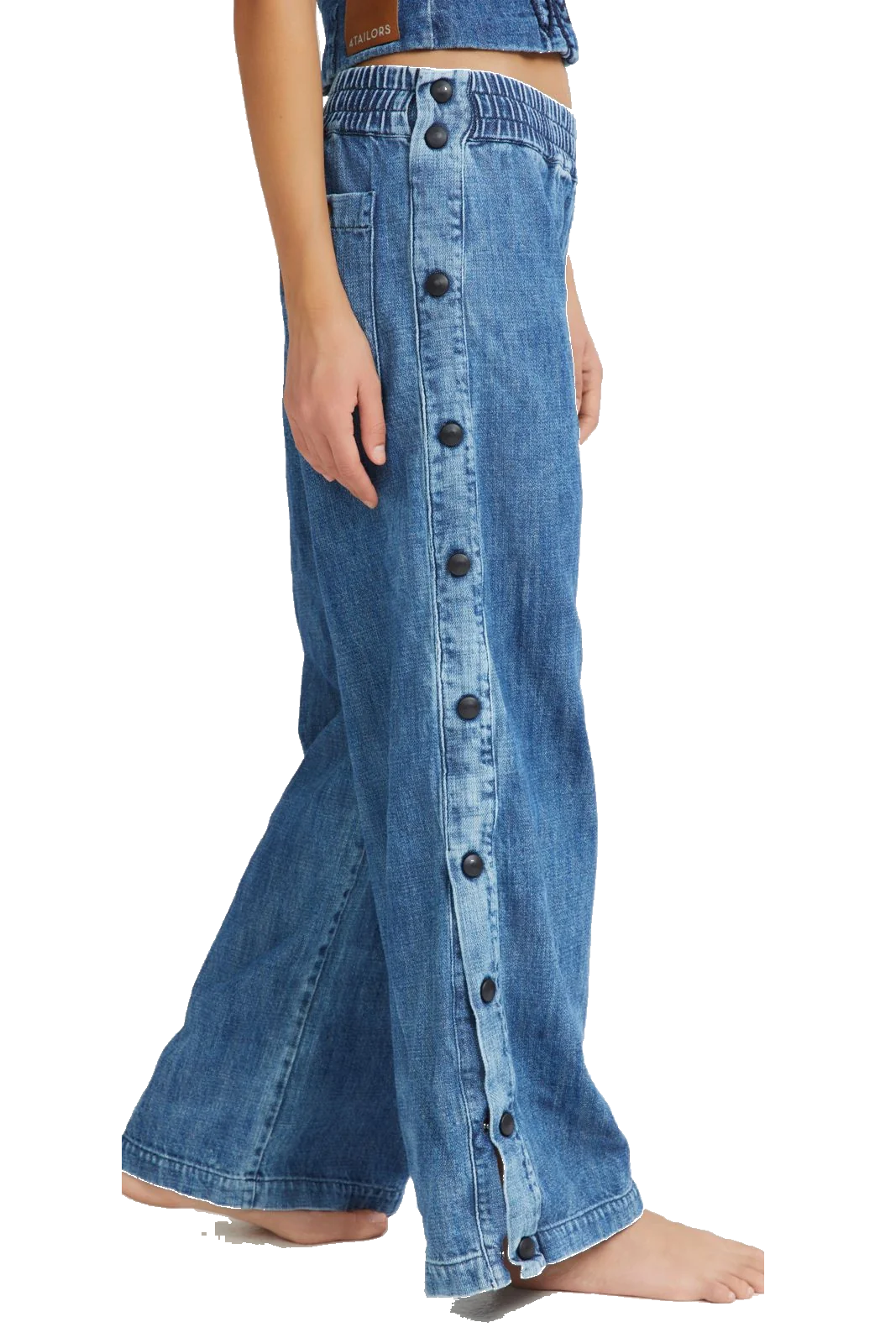 A person wearing wide-leg blue denim pants with a vertical row of large dark buttons down the front, shown against a plain white background.