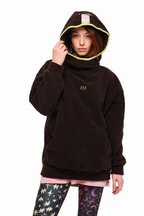 A model wearing a dark brown fleece hoodie with a bright yellow-green hood lining and a small yellow-green 'RPC' logo on the chest, paired with pink and patterned leggings, against a plain white background.