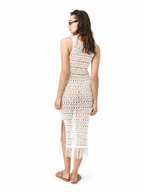 A woman wearing a sleeveless crochet knit midi dress with fringe, shown from the back against a plain white background.