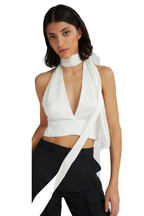 A model wearing a white halter wrap top with a high neck and a long draped tie detail, paired with black pants, against a plain white background.