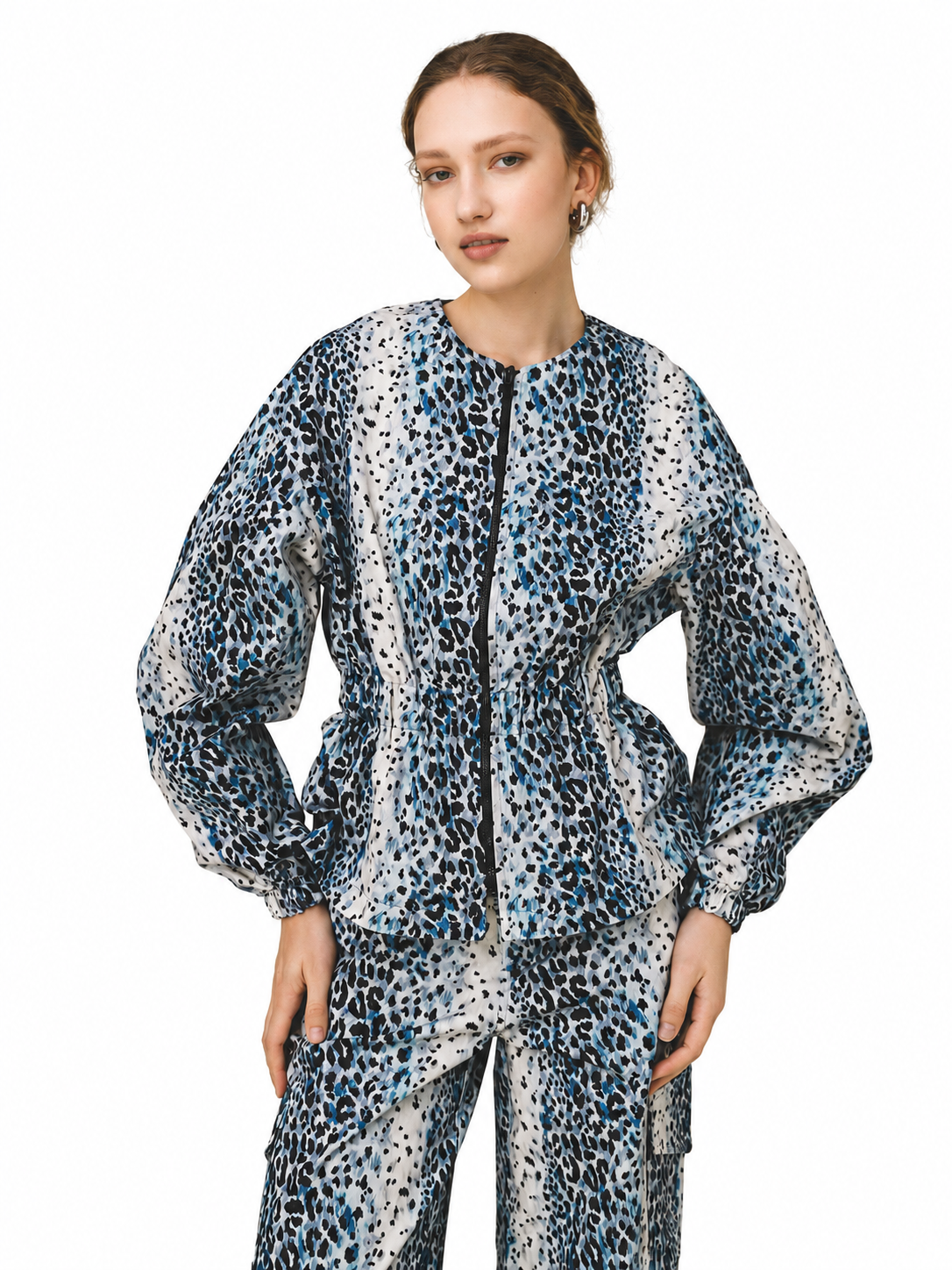 A model wearing a matching two-piece outfit featuring a blue, black, and white leopard print jacket and pants, set against a plain white background.