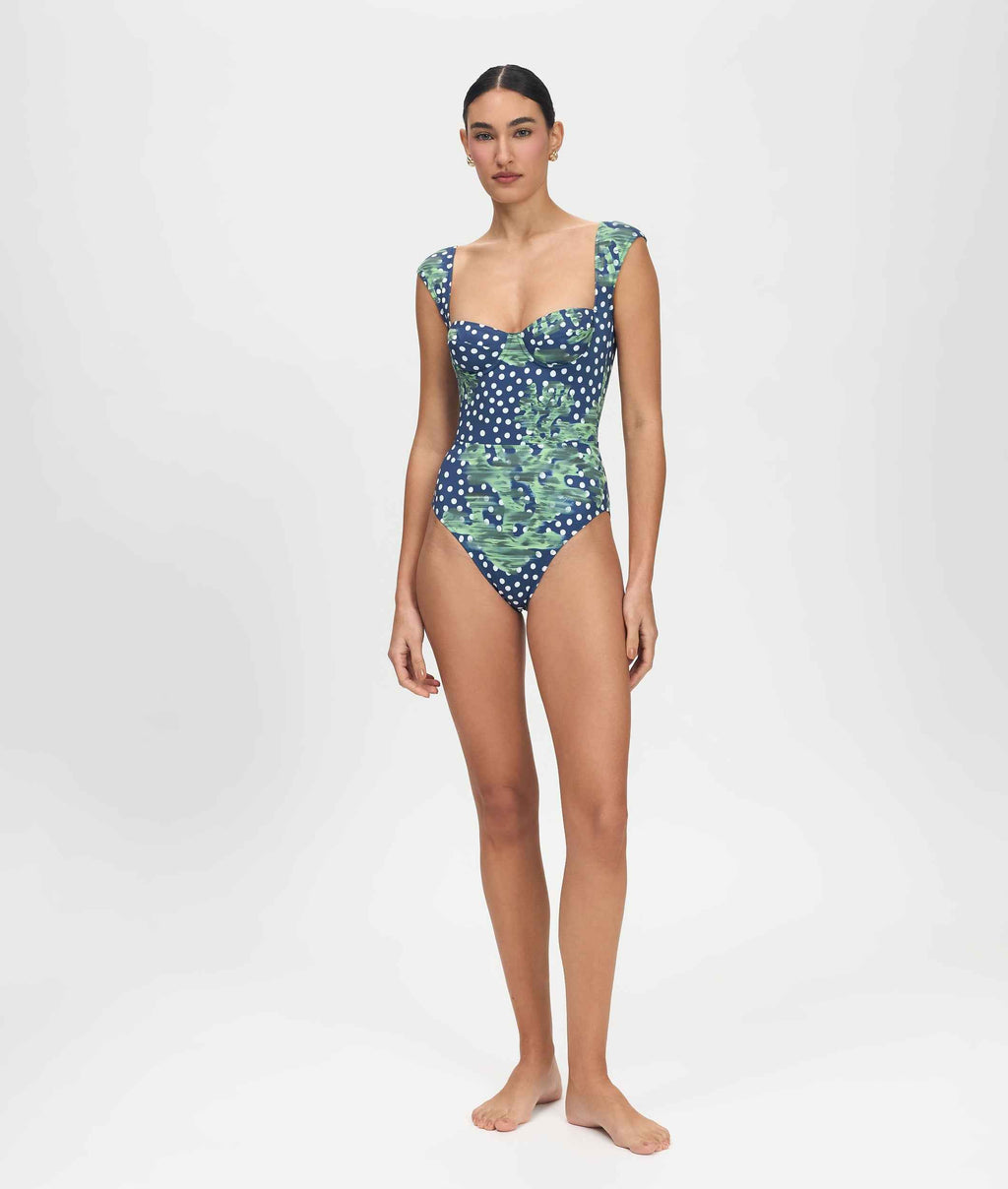 Woman wearing a blue and green patterned one-piece swimsuit on a white background