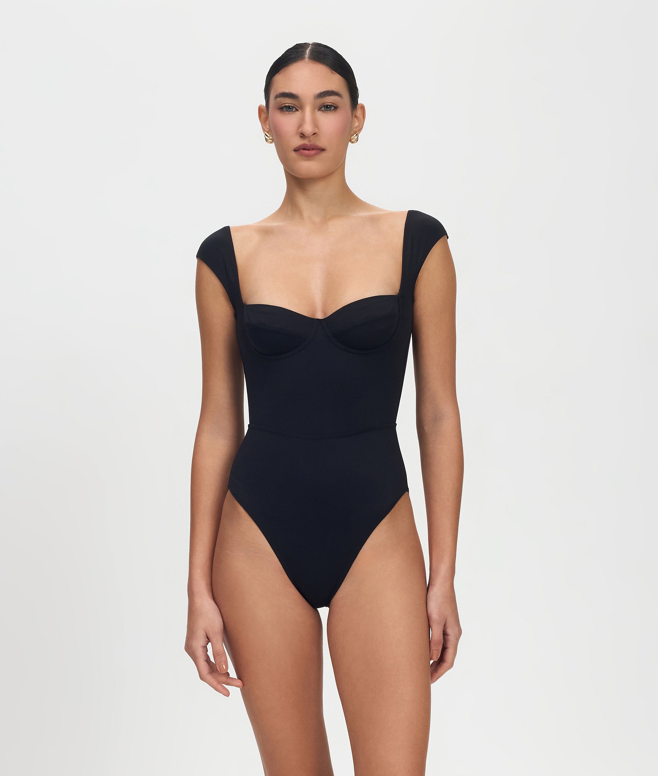 Woman wearing a black swimsuit against a plain background