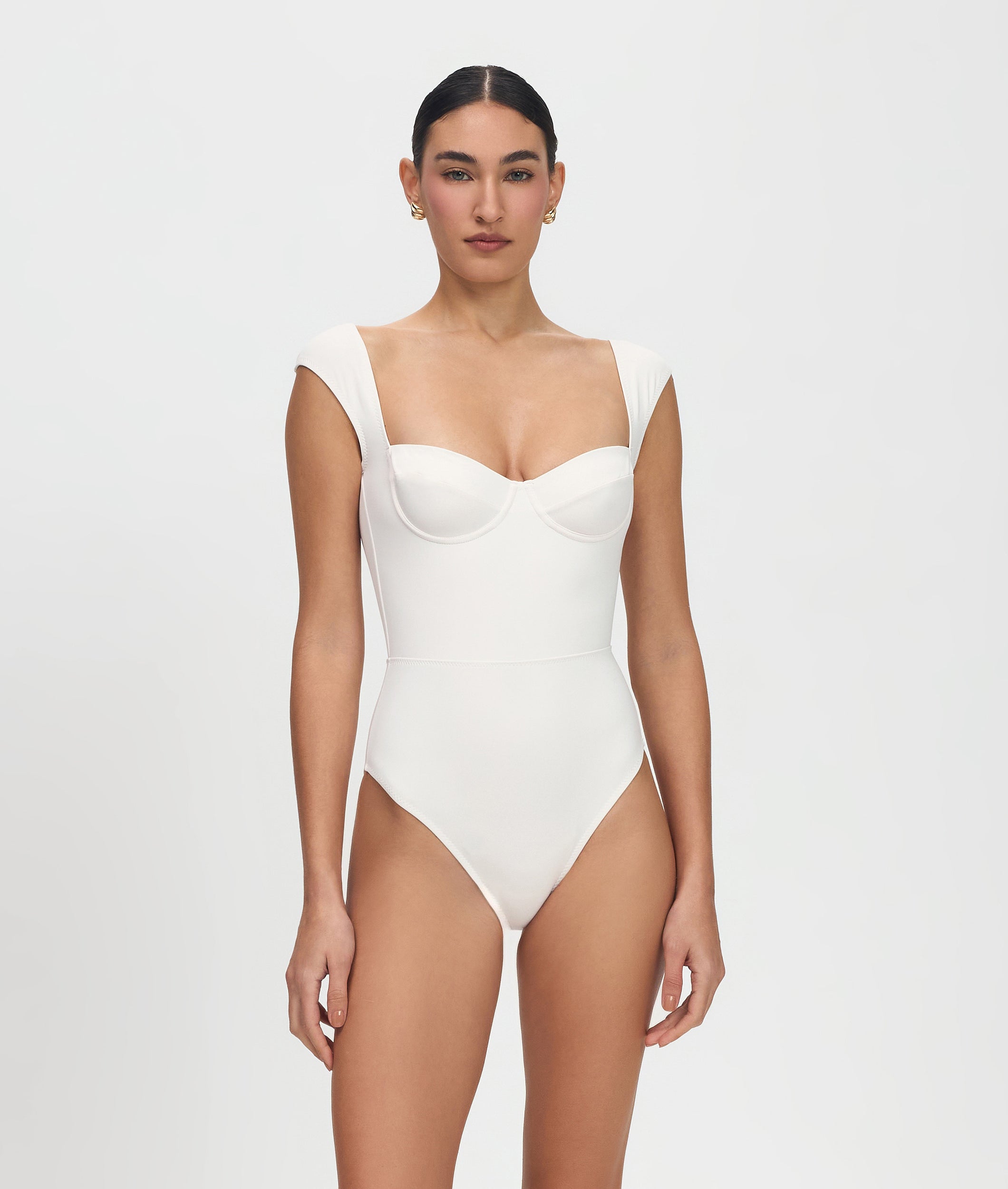 Woman wearing a white one-piece swimsuit on a plain background