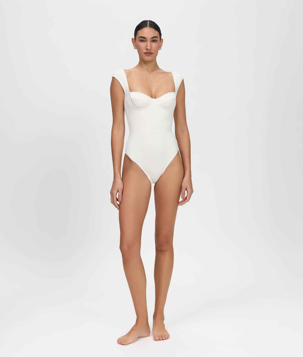 Person wearing a white one-piece swimsuit on a plain background