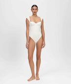 Person wearing a white one-piece swimsuit on a plain background