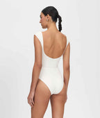 Woman wearing a white swimsuit with a plain background