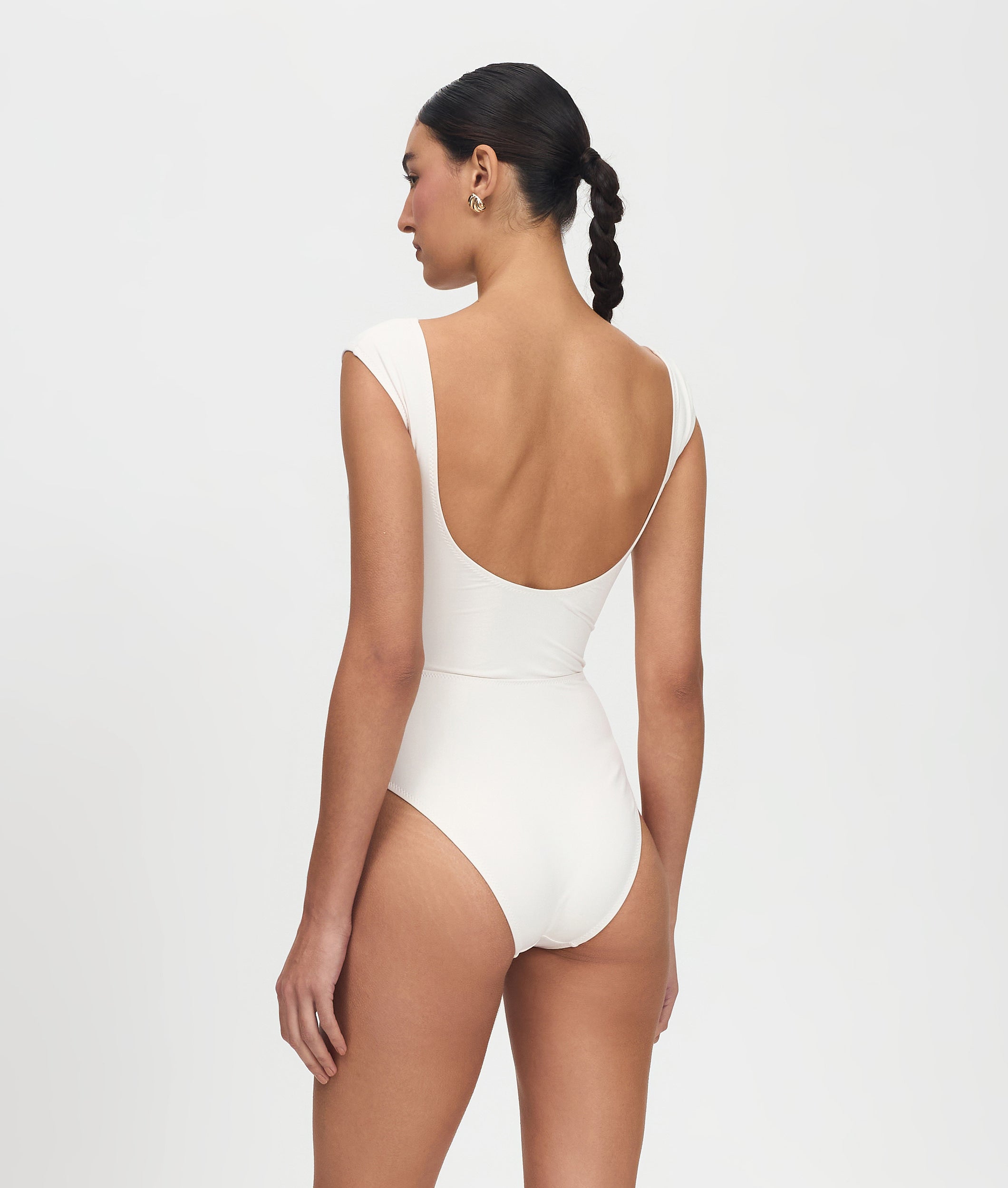 Woman wearing a white swimsuit on a light gray background