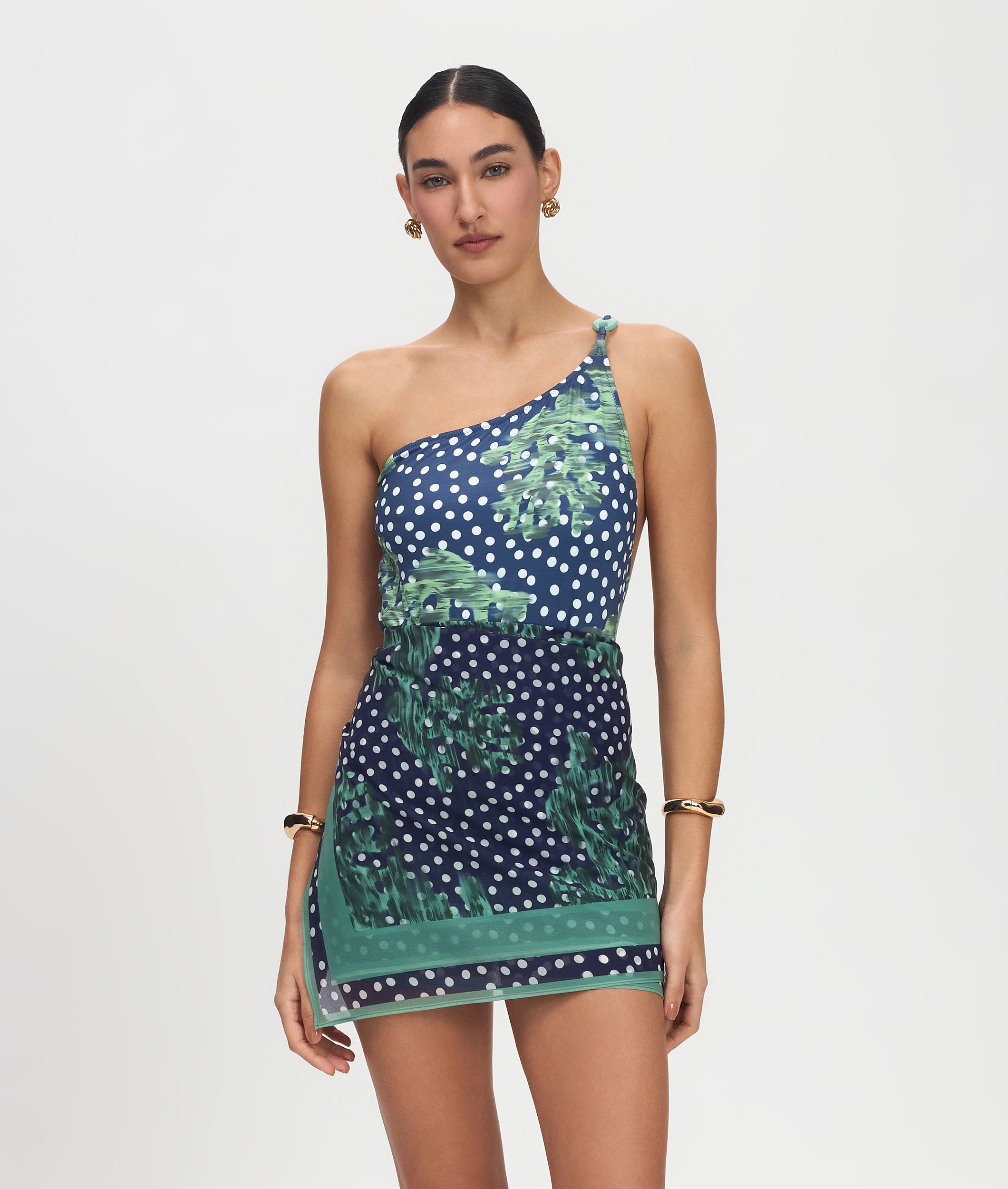 Woman wearing a one-shoulder dress with a blue and green pattern on a white background