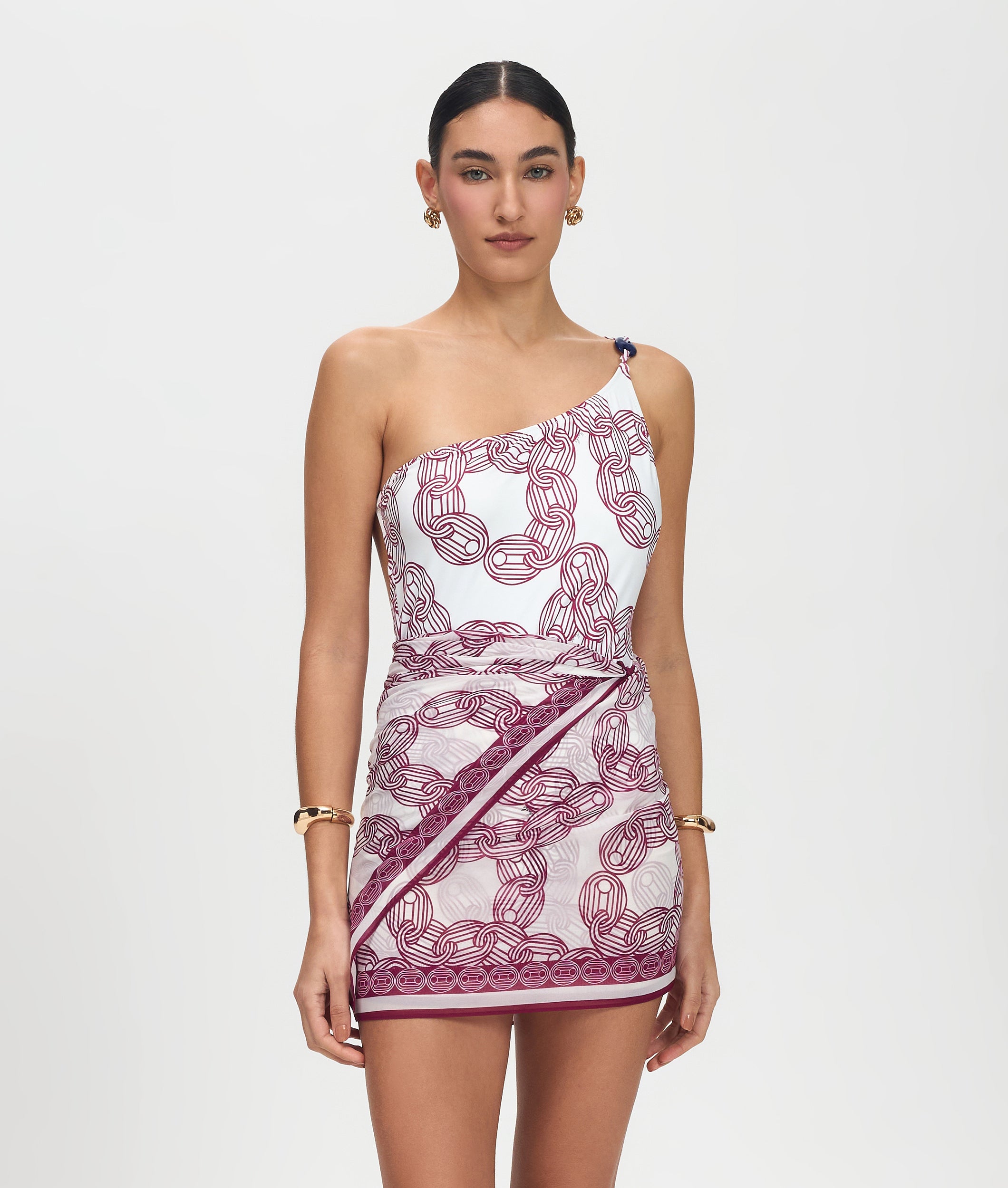 Woman wearing a one-shoulder dress with a chain pattern on a white background