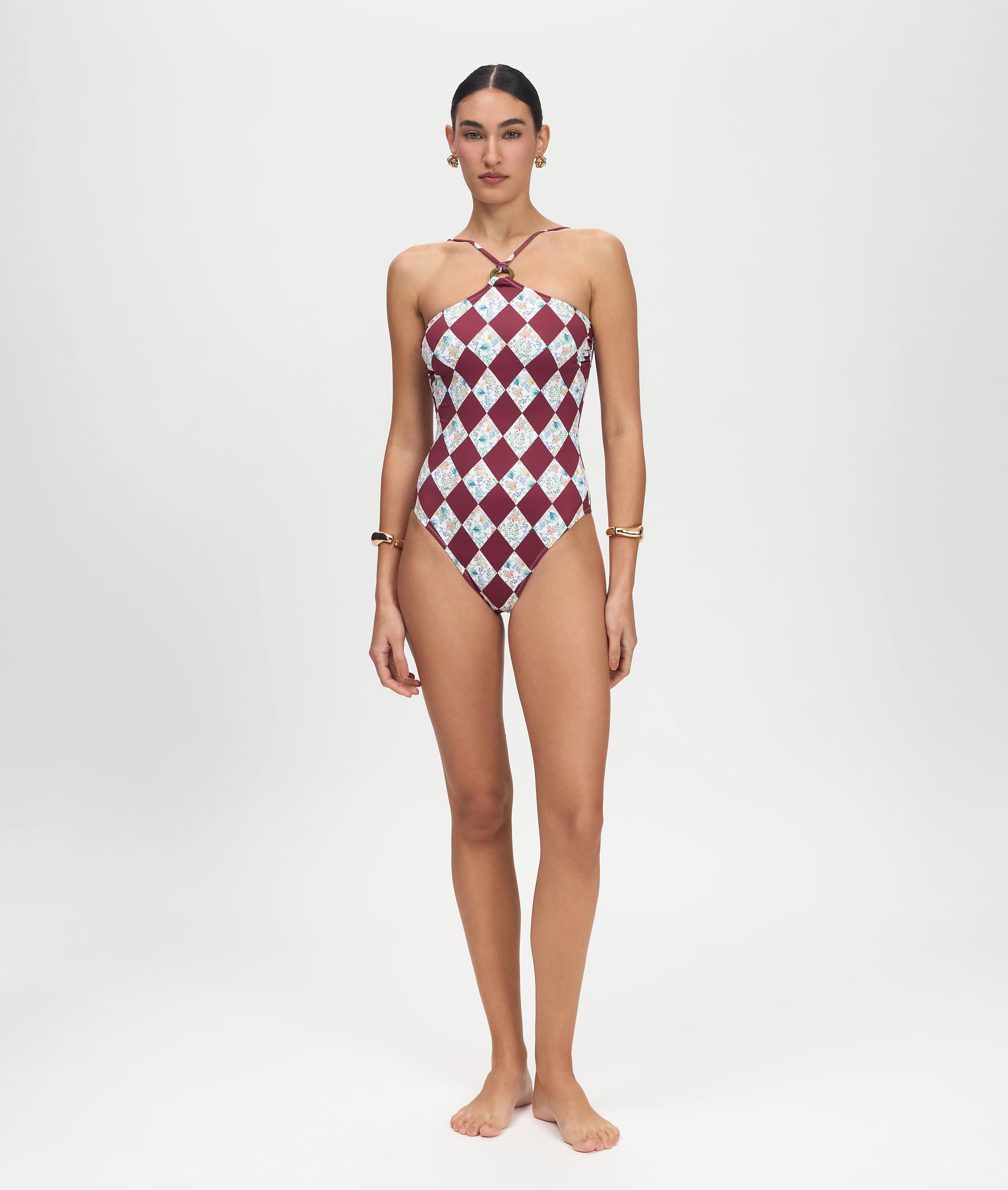 Model wearing a one-shoulder swimsuit with a red and white checkered pattern on a white background