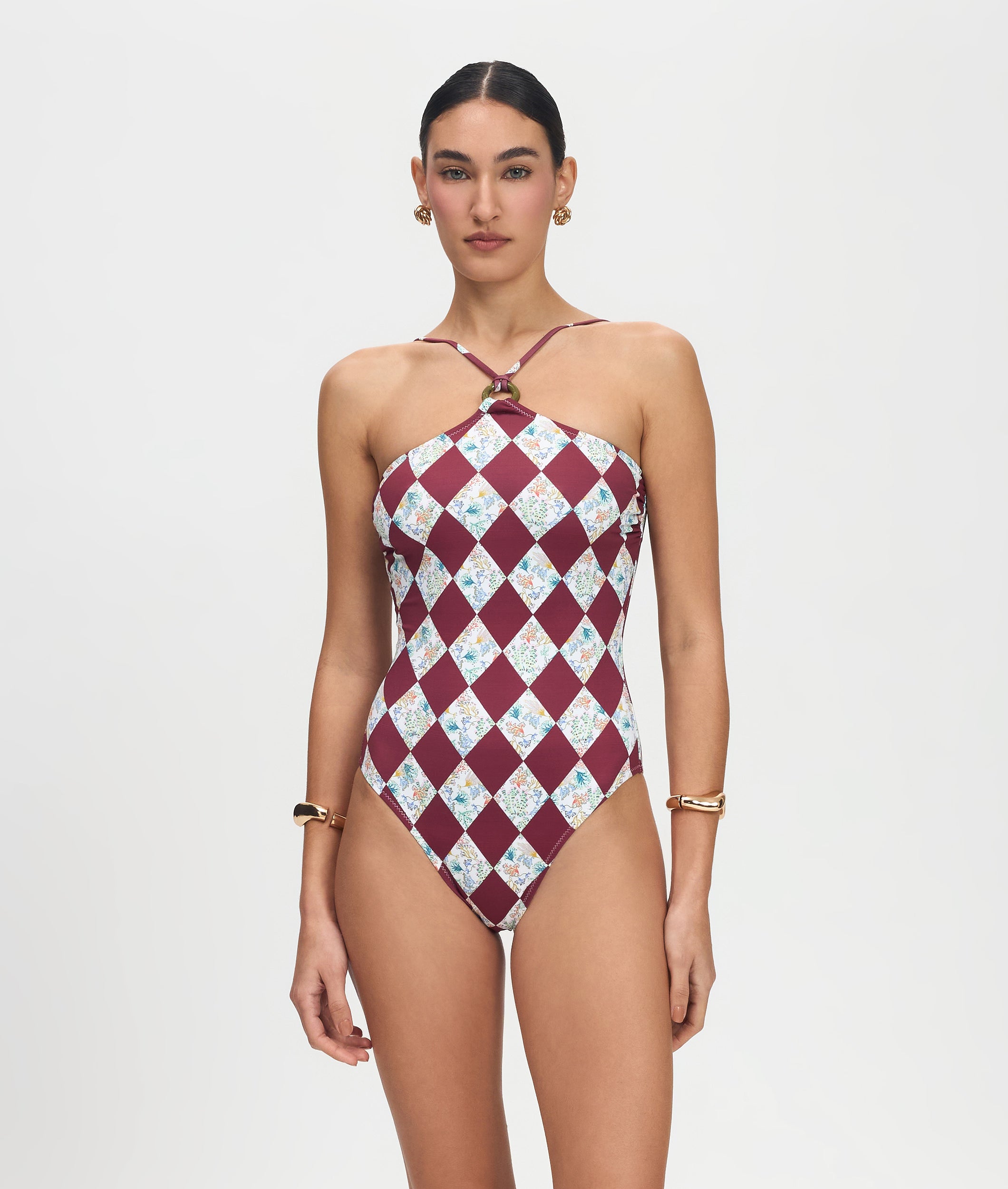 Woman wearing a patterned one-piece swimsuit on a plain background