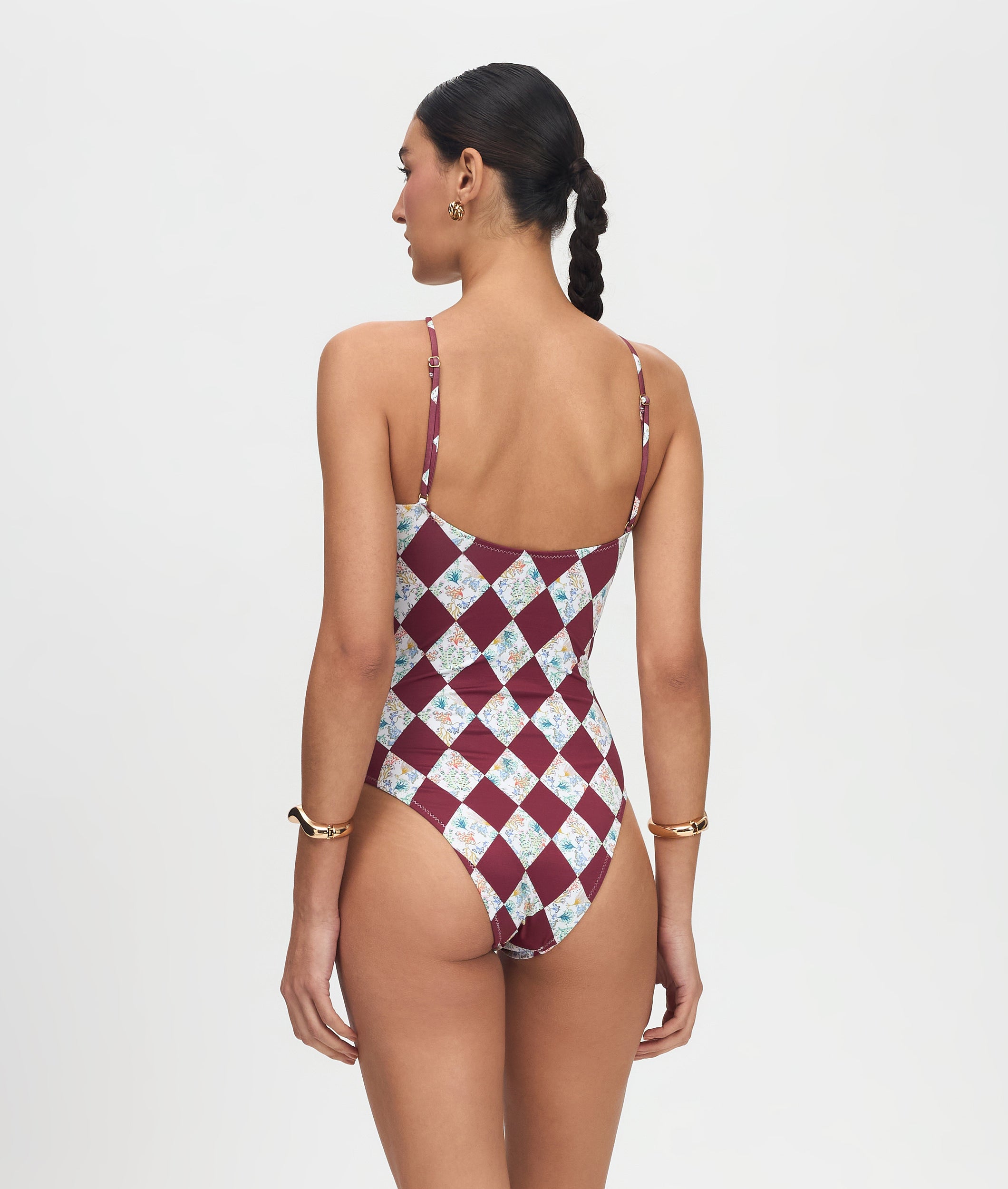 Woman wearing a patterned one-piece swimsuit on a plain background