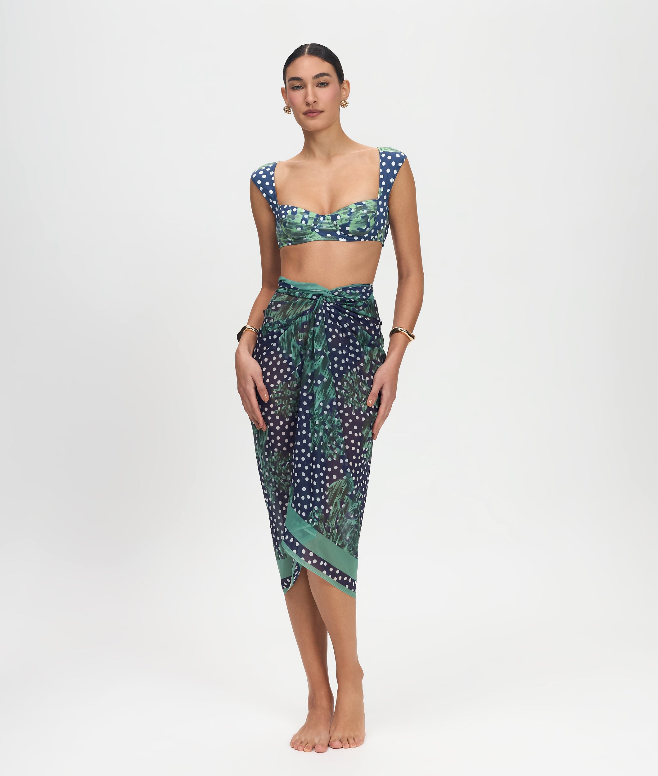 Woman wearing a green and blue patterned top and skirt on a white background