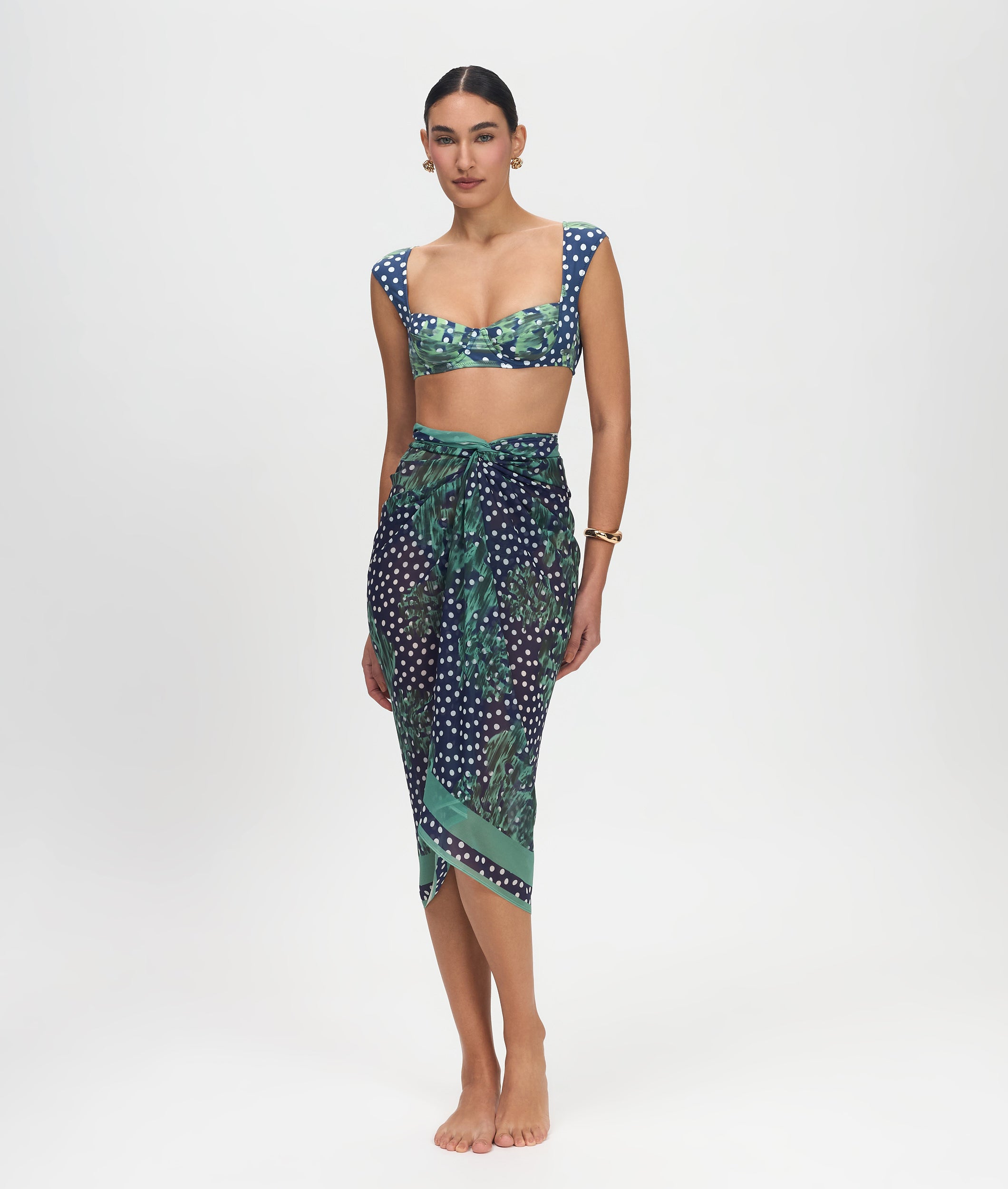 Woman wearing a green and blue patterned top and skirt on a white background