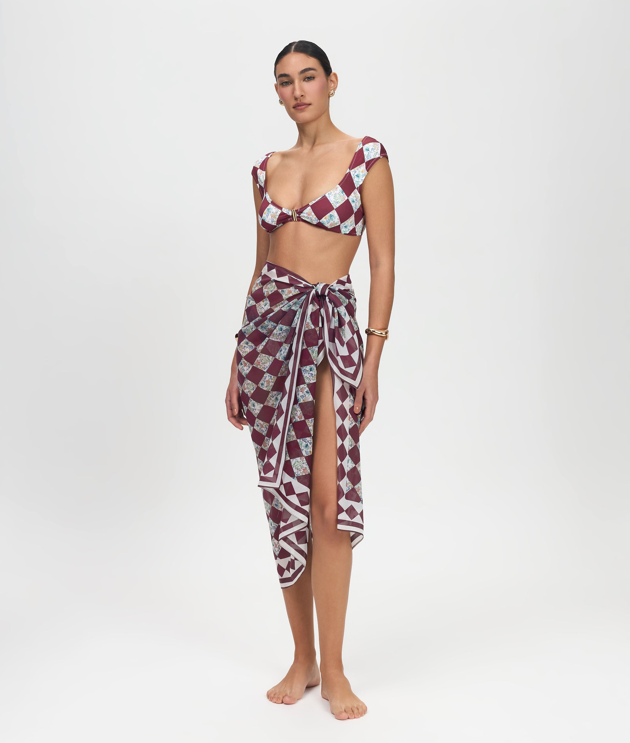 Woman wearing a patterned bikini and sarong on a white background