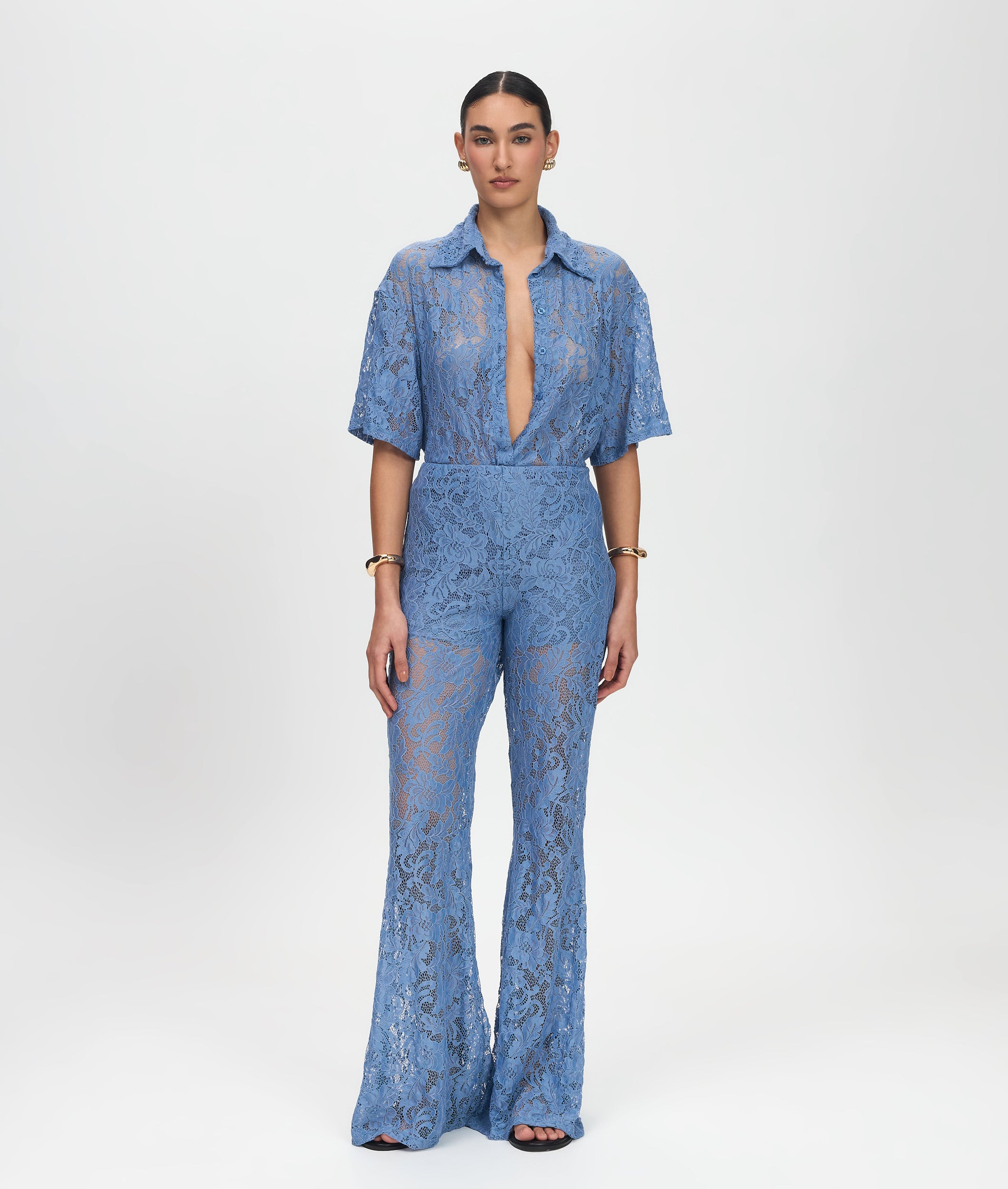 Woman wearing a blue lace jumpsuit on a white background