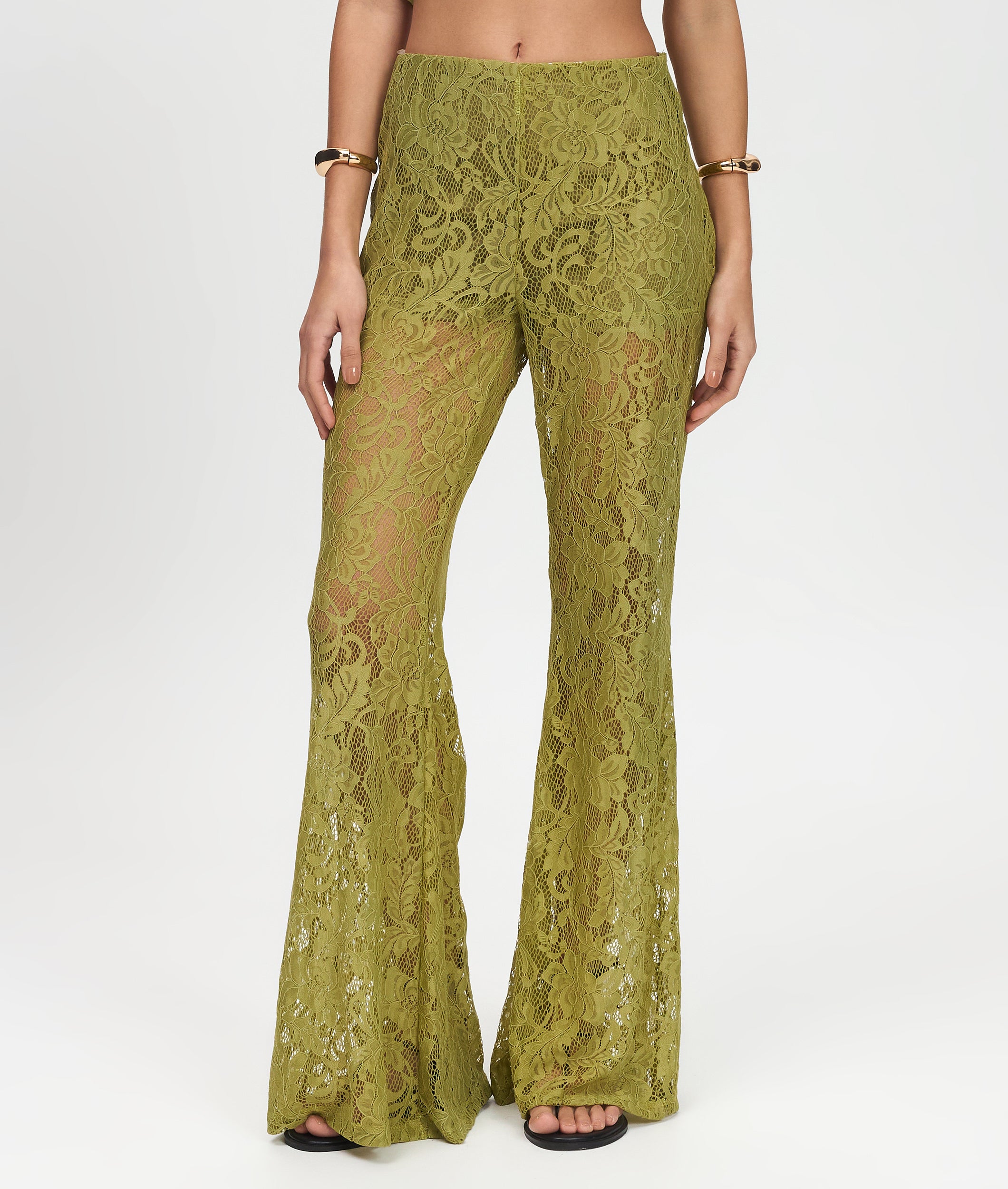 Green lace pants worn by a person on a white background