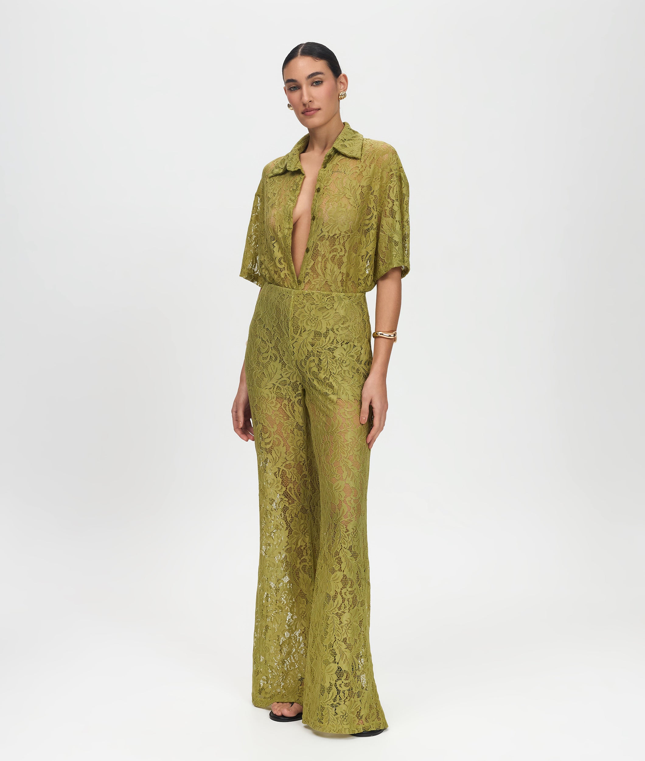 Woman wearing a green lace jumpsuit on a white background