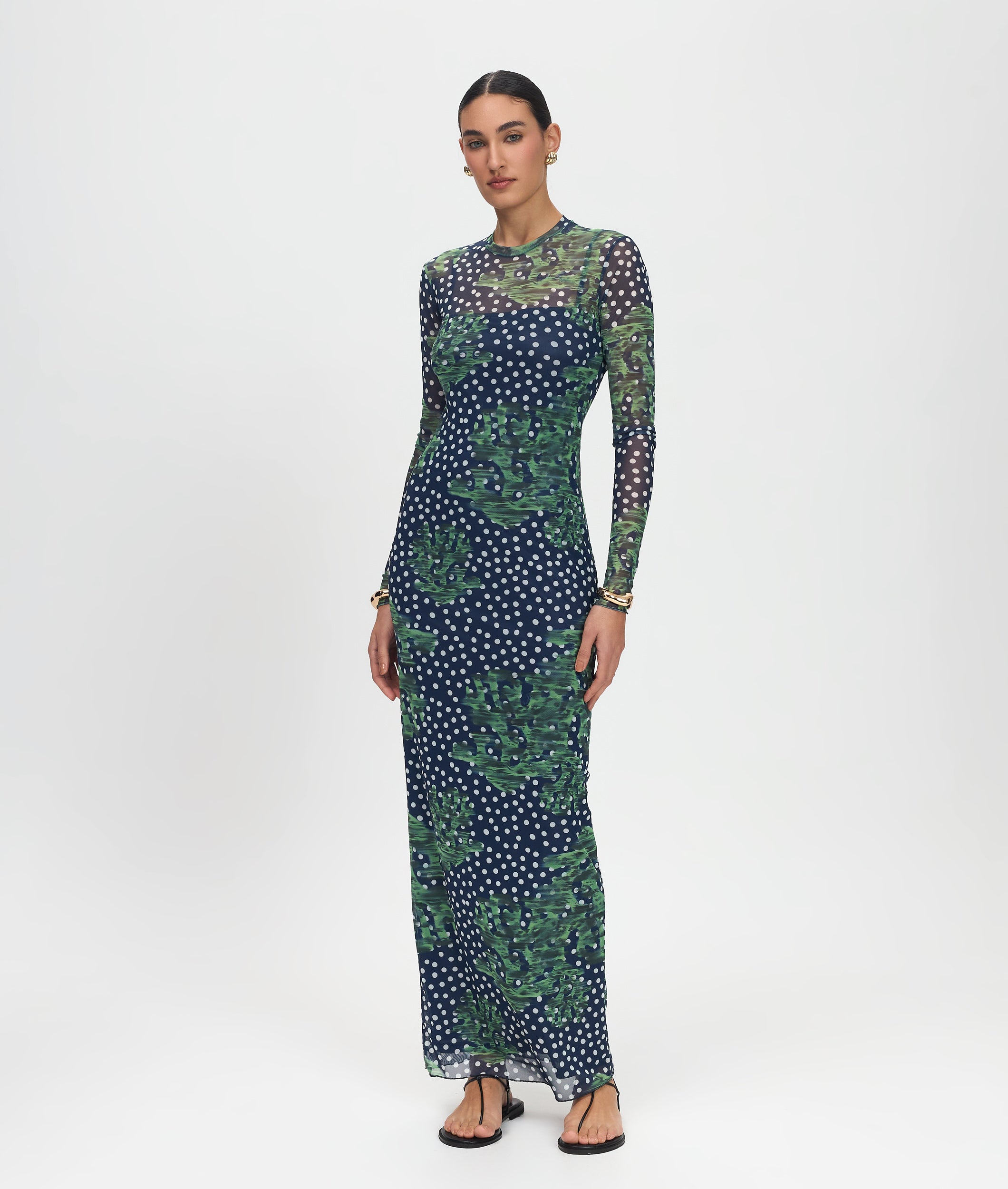 Woman wearing a long-sleeve, patterned dress on a white background